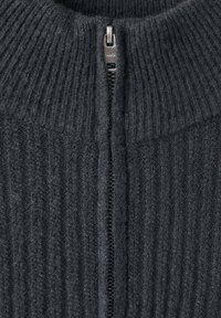 Maglione a coste di un grigio scuro con collo alto e zip anteriore. Tessuto dalla texture particolare con chiusura a zip liscia.