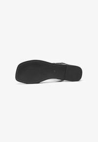 Sole di scarpa nera realizzata in gomma liscia. Presenta una forma curvata, un motivo testurizzato e una delicata cucitura lungo i bordi.