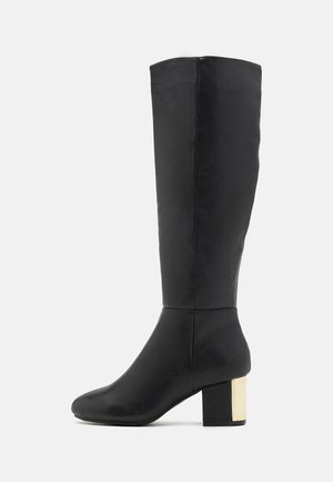 Botte en cuir noire hauteur genou avec bout arrondi et talon bloc, ornée d'un accent métallique doré à l'arrière.