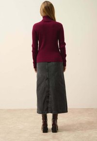 Burgundin värinen ribbireunainen turtleneck-neulepaita, joka on yhdistetty tummansiniseen midihameseen. Sisältää takana olevan halkion ja paksupohjaiset saappaat.