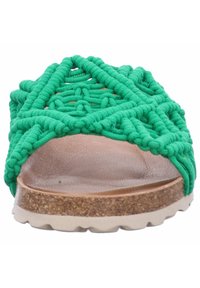 Sandalia de tira con diseño trenzado verde, con plantilla de corcho, superficie texturizada y una suela que presenta un patrón de olas para mayor agarre.