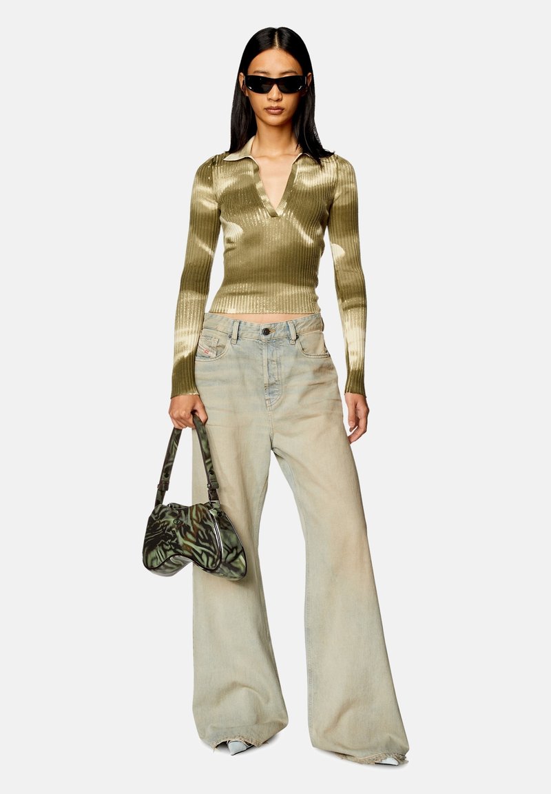 Haut en tricot côtelé vert olive avec décolleté en V, associé à un jean large bleu clair. Sac à main à motifs décoratifs, des lunettes de soleil complètent le look.