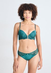 Teal lingerie set featuring a molded bra with lace trim and adjustable straps, paired with lace-accented briefs. Smooth fabric texture.