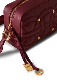 Borsa a tracolla in pelle bordeaux con design trapuntato, dettagli in hardware oro, chiusura con zip e dettagli testi sul manico.