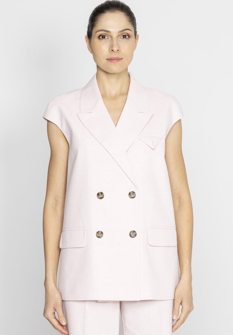 Jasnoróżowa kamizelka podszyta, krótki rękaw, złote guziki, klapki i kieszenie z przodu. Gładki materiał, dopasowany krój.