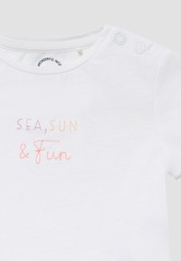 Witte katoenen shirt met twee drukknoopjes op de schouder, met gekleurde geborduurde tekst: "ZEE, ZON & Plezier."