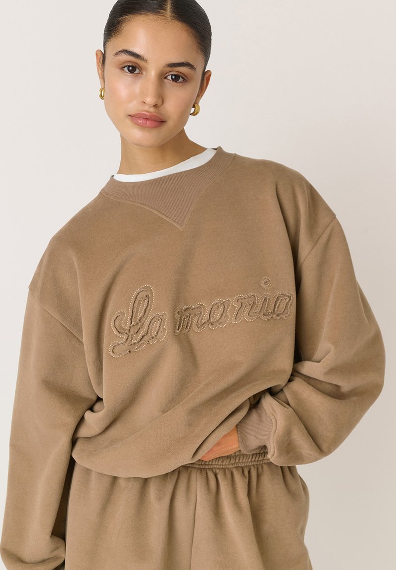 sweatshirt maro supradimensionat cu text brodat "La toria", având un decolteu rotund cu nervuri și un material moale, texturat.