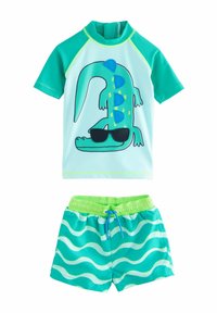 Svømmetøj bestående af en kortærmet turkise rash guard med et grønt krokodille-design i solbriller, parret med matchende shorts med bølgemønster.