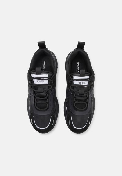 Chaussures de sport noires avec un dessus en mesh, fermeture à lacets, accents texturés et des détails réfléchissants blancs le long de la semelle et des côtés.