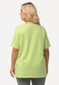T-shirt in cotone verde lime con maniche corte, scollatura rotonda e vestibilità rilassata. Tessuto liscio senza motivi o dettagli.