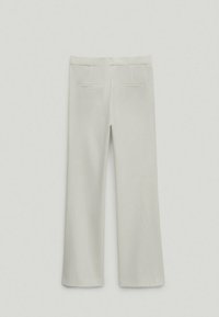 Pantalons beige clair avec une coupe droite, dotés de deux poches arrière et d'une texture lisse. Aucun motif ni élément en métal visible.