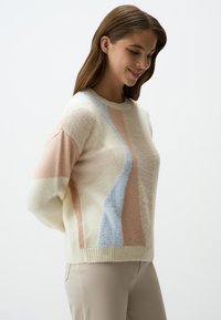 Maglione lavorato a maglia color crema con colori pastello: rosa, blu e arancione, dalla morbida consistenza, con collo a coste e motivi diagonali decorativi.
