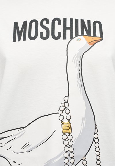 Λευκή μπλούζα με γραφικό ενός χήνου που φοράει περιδέραιο με πέρλες, με την επωνυμία «MOSCHINO» τυπωμένη πάνω σε έντονα μαύρα γράμματα.