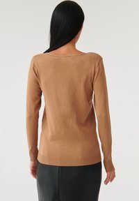 Pull marron à manches longues avec un col légèrement arrondi et des poignets côtelés. Le matériau semble doux avec une texture lisse.