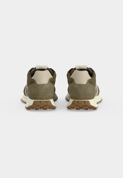 Paire de baskets vert olive et beige vues de dos avec des semelles brunes texturées et des languettes au talon sur un fond uni.