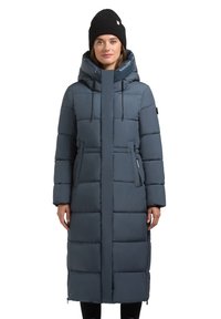 Tamsiai mėlynas šiltas ilgas paltas su dekoratyviniais siuvinėtais segmentais, užtrauktukais užsegamomis kišenėmis, aukštu apykakle ir reguliuojama kapišonu. Dėvimos su juoda megzta skrybėle.