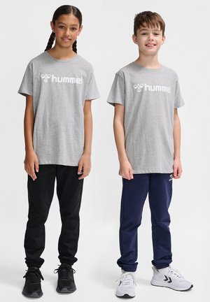To børn står side om side iført grå "hummel" T-shirts, sorte og navy joggingbukser og sorte og hvide sneakers på en hvid baggrund.