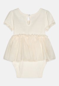 Bodysuit à manches courtes en crème avec un haut texturé et un peplum en tulle superposé, présentant une fermeture à bouton au dos et des bords de manches froncés.