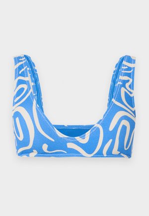 Sportski grudnjak plavo-bijelog apstraktnog uzorka s širokim naramenicama i okruglim izrezom na bijeloj pozadini.