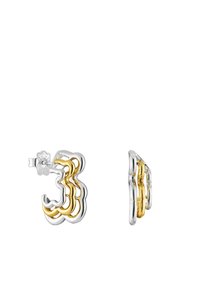 Pendientes de aro en plata y oro que presentan diseños ondulados y en capas. Los pendientes combinan plata pulida con acentos en oro para crear un contraste visual.