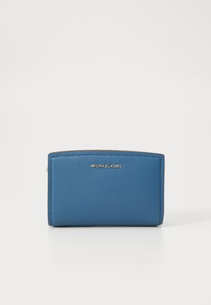 Portafoglio blu in pelle con una texture liscia, design con parte superiore curva e logo dorato "MICHAEL KORS" sulla parte anteriore. Forma compatta e rettangolare.