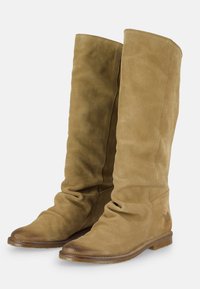 Botas de ante color vainilla hasta la rodilla con un diseño holgado, punta redondeada, textura suave y suela de madera plana con un detalle de marca mínimo.