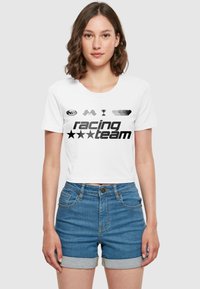 Hvit, kortermet t-skjorte med svarte grafikker, inkludert et racing-tema logo, rutete flagg, trofé og hjerteformer. Kombinert med denimshorts.
