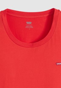 T-shirt in cotone rosso con scollo a girocollo, caratterizzato da un piccolo logo Levi's ricamato sul lato sinistro del petto. Tessuto liscio, design semplice.