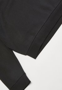 Felpa nera caratterizzata da un tessuto liscio e opaco, con una vestibilità comoda, polsini a costine e orlo dritto. Nessun motivo o logo visibile.