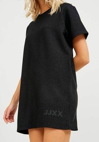 Black short-sleeve dress with a loose fit, made of textured fabric that sparkles. Features a logo "JJXX" in a subtle design near the hem.