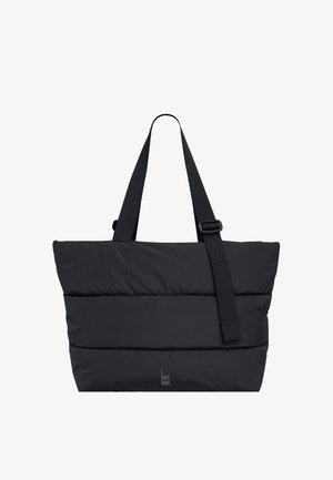 Sort quiltet tote-taske med to skulderstropper, hvoraf den ene er justerbar, og med et lille "GOT BAG." logo nær bunden i midten.