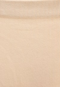 Κοντινό πλάνο μπεζ υφάσματος με ριγέ υφή και κάθετες γραμμές, με μια διακριτική πτυχή κοντά στην κορυφή.