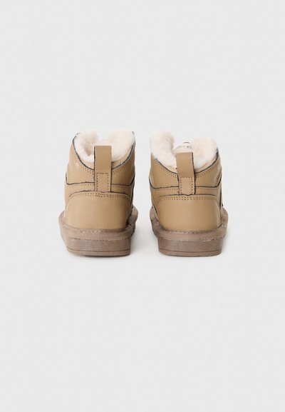 Tanfarbene Leder-Stiefeletten mit Futter aus Kunstfell und einer strukturierten Gummisohle. Mit einer Schlaufe an der Ferse für ein einfaches An- und Ausziehen.