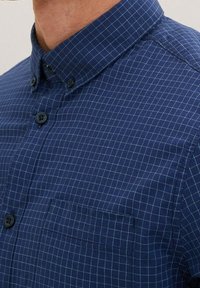 Camicia blu navy con bottoni, caratterizzata da un piccolo motivo a quadri, con colletto, taschino sul petto e bottoni scuri. Tessuto in cotone.