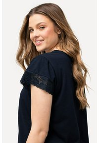 Camiseta azul marino de manga corta con borde de encaje floral. Tejido suave, corte relajado y escote redondo. Diseño simple y elegante.