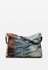 Torba o wzorze przypominającym dżins z brązowym skórzanym paskiem, wyposażona w kieszeń na zamek i ozdobione sznurowaniem detale po bokach. Materiał ma teksturowane wykończenie.