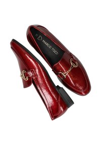 Glanzende rode vrouwen loafers met gouden paardbit-detail en zwarte zolen, weergegeven vanuit zij- en bovenaanzicht op een witte achtergrond.