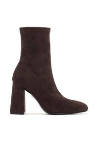 Stivaletto in suede marrone con punta affusolata e tacco a blocco. Texture liscia e design senza cuciture senza hardware o dettagli visibili.