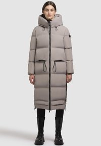 Ljust grå, vadderad lång kappa med huva, frontdragkedja, dragsko i midjan och svarta detaljer; har en strömlinjeformad silhuett och långa ärmar.