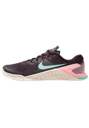 Chaussure de sport Nike violet foncé avec un swoosh turquoise, un soutien de talon rose et une semelle blanche texturée, vue de côté sur fond blanc.