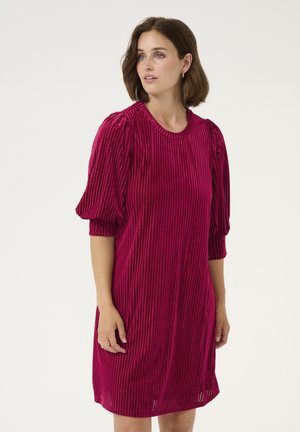 Fuksijas kleita ar vertikālu ribu tekstūru, apaļu kakla izgriezumu un pūkainām īsām piedurknēm. Līdz viduklim, attēlota uz neitrāla fona.