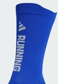 Blauwe sportsocken met ribbeltextuur en witte tekst "RUNNING". De boord heeft een licht taps toelopend ontwerp. Zacht, rekbaar materiaal.