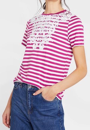 Camiseta de rayas rosa y blanca con mangas cortas, que presenta un intrincado detalle de encaje blanco en el escote y un corte relajado.