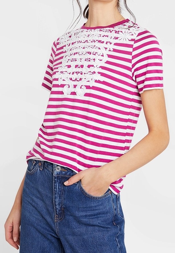 Camiseta de rayas rosa y blanca con mangas cortas, que presenta un intrincado detalle de encaje blanco en el escote y un corte relajado.
