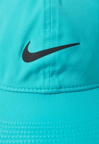 Tyrkysová čiapka z hladkej textílie, s čiernym logom Nike swoosh, so šitými detailmi a zakriveným šiltom.