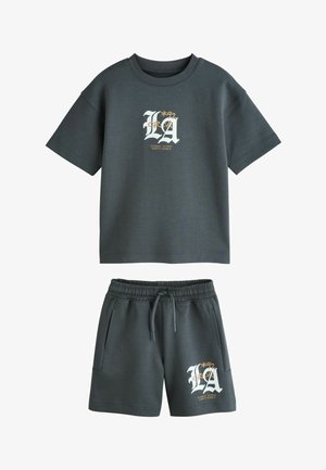 Sötétszürke rövid ujjú póló és rövidnadrág szett elasztikus derékpánttal, zsebekkel és fehér-sárga "LA 1992 Los Angeles California" feliratos grafikával.