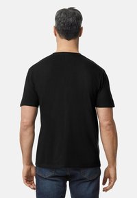 Camiseta negra de manga corta con un clásico cuello redondo, fabricada en suave algodón y con un diseño liso en la parte posterior, combinada con vaqueros azules.