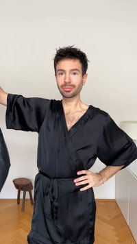 Zwarte satijnen kimono-robe met wijde mouwen en een ceintuur, met een gladde textuur en een knielengte ontwerp.