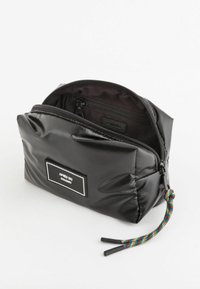 Czarna wodoodporna torba o miękkiej, pikowanej fakturze, z zamkiem błyskawicznym na górze i kolorową plecioną zasuwką. Etykieta: "APRES SKI DOLOMITI."