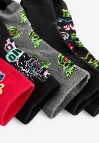 Set med fem strumpor i olika färger: röd, svart och grå; med grafiska mönster som inkluderar monster och lekfulla designer; ribbad textur.